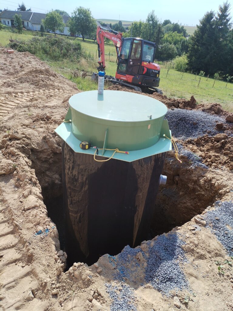 Foto usazené domovní čističky odpadních vod na realizaci u klienta. ČOV je usazená na štěrkovém lože ve výkopu a připravená k obsypu a napojení.